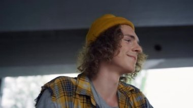 Kaykay parkında bisikletle antrenmandan sonra dinlenen gülümseyen genç. Kıvırcık saçlı adam.