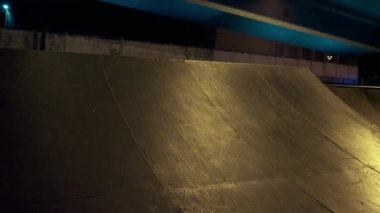 Kentsel kaykay parkında gece vakti BMX bisikleti süren olağanüstü bir adam. Bmx sürücüsü pratik yapıyor. 