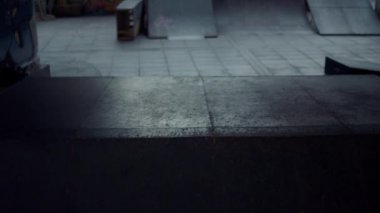 Genç scooter sürücüsü kaykay parkındaki rampada numaralar yapıyor.. 