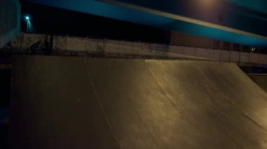 Aktif gençler gece kaykay parkında scooter kullanıyor. Sportif adam zıplıyor. 