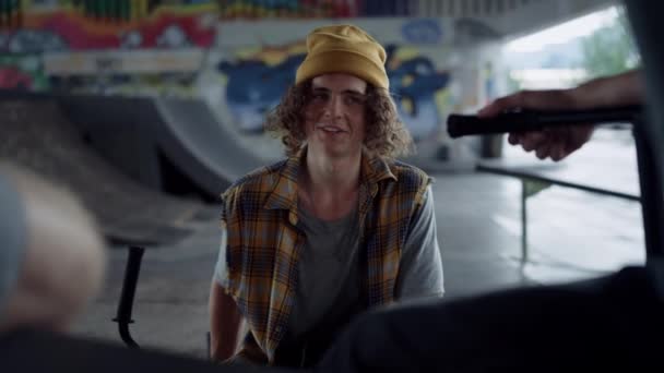 Lächelnde Freunde genießen das gemeinsame Gespräch an der Graffiti-Wand im Skatepark. — Stockvideo