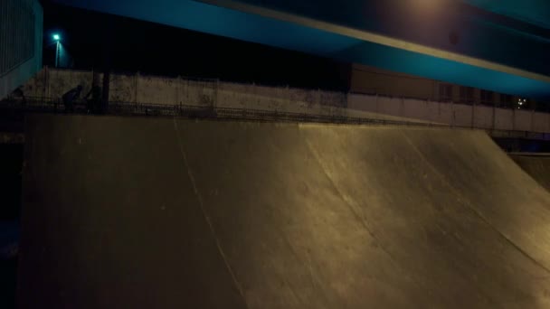 Aktif gençler gece kaykay parkında scooter kullanıyor. Sportif adam zıplıyor. — Stok video