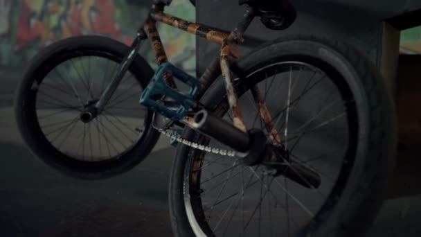 Bmx fietsenstalling tegen helling bij skatepark graffiti muur. Draaien van fietswielen — Stockvideo