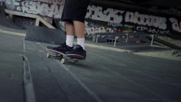 Sportovní muž dělá cvičení na skate board v skateparku s graffiti stěnou. — Stock video