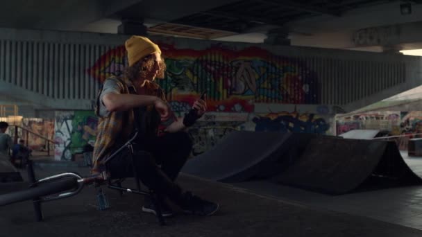Lässiger Mann macht Selfie-Foto mit Smartphone an Graffiti-Wand im Skatepark. — Stockvideo