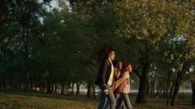Aile güz parkında yürüyor, altın güneş ışığında el ele tutuşuyorlar..