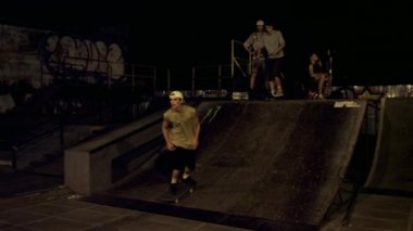 Gençler gece kaykay parkında duvar yazısıyla rampadan atlıyorlar.. 