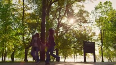Afrika kökenli Amerikalı ebeveynler el ele tutuşup birlikte yeşil park geçidinde koşuyorlar..