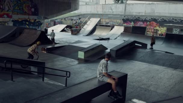 Des adolescents sportifs passent du temps ensemble au skate park urbain avec des graffitis. — Video