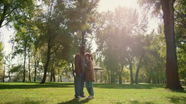 Boldog gyermek apa áll együtt a zöld park területén arany napfényben. — Stock videók