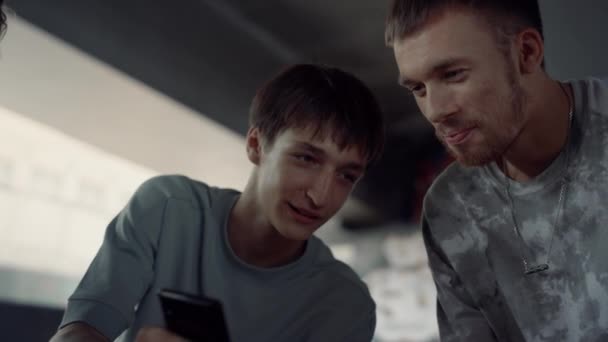 Amigos positivos desfrutando de mídias sociais no celular no parque de skate. — Vídeo de Stock