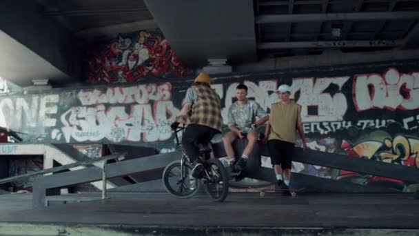 Homem desportivo executando truque de salto na bicicleta bmx no parque de skate com graffiti. — Vídeo de Stock