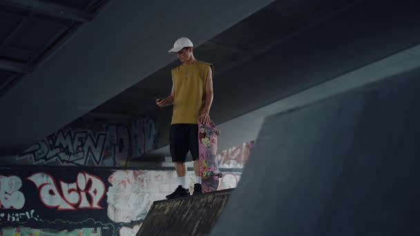 Hombre atractivo usando celular para autorretrato en skate park con graffiti. — Vídeos de Stock