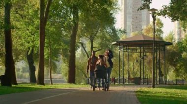 Mutlu aile bebek arabasıyla yeşil yolda yürüyor. Dikkatsiz ebeveynliği sevmek.