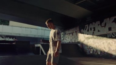 Kaykay parkında paten kayan aktif bir adam duvarda grafiti var.. 