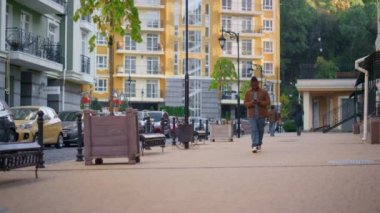 Şehir caddesinde akıllı telefon kullanan mutlu bir adam. Şehir gezgini etrafta dolaşıyor.