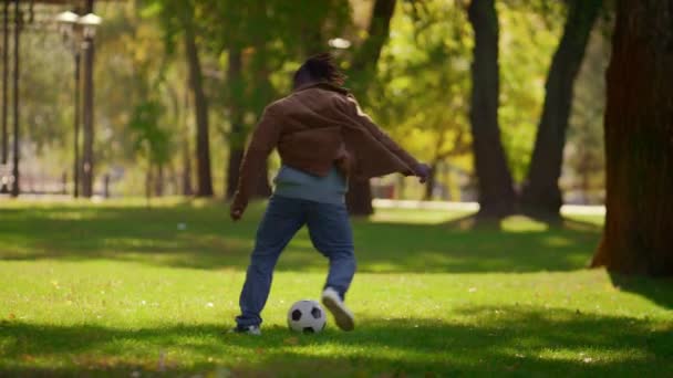 Мужчина играет в футбол в теплый весенний день. Фокус-плеер, тренирующийся на открытом воздухе — стоковое видео