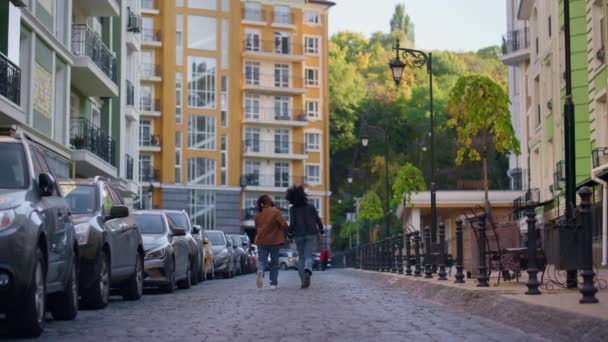 Радісна пара, яка досліджує місто, тримає руки за спину. Міські мандрівники йдуть вулицею . — стокове відео