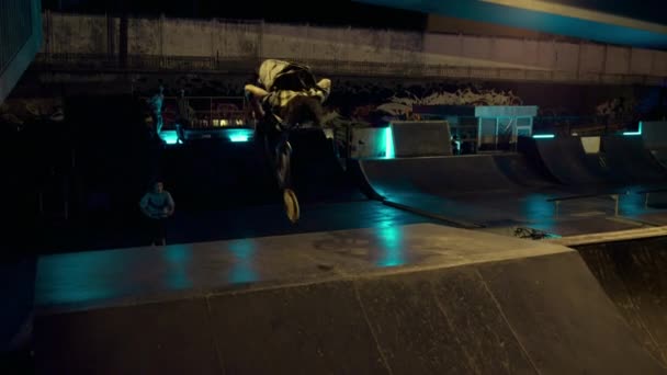 Sportowi nastoletni jeźdźcy skaczący razem na skuterze i rowerze bmx w skateparku. — Wideo stockowe