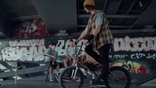 Mladý hipster závodní bmx kolo v skate parku s graffiti na zdi. — Stock video