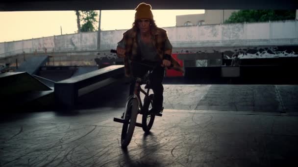 Young man riding bmx bike at urban skatepark. Biker jumping outdoors. — Stock Video