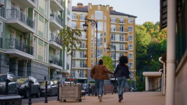 Pareja feliz caminando ciudad moderna zona residencial vista trasera. Hombre haciendo salto. — Vídeos de Stock