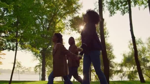 Niño caminando cogido de las manos de los padres en el parque verde. Feliz tiempo en familia al aire libre — Vídeos de Stock