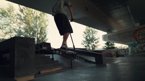 Adolescentes pilotos praticando juntos em scooter e skate skate cidade skatepark. — Vídeo de Stock