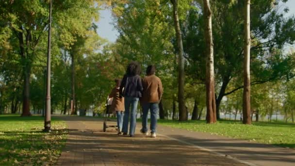 Lässige Eltern gehen Herbst Park Rückansicht. Glückliches Familienwochenende. — Stockvideo