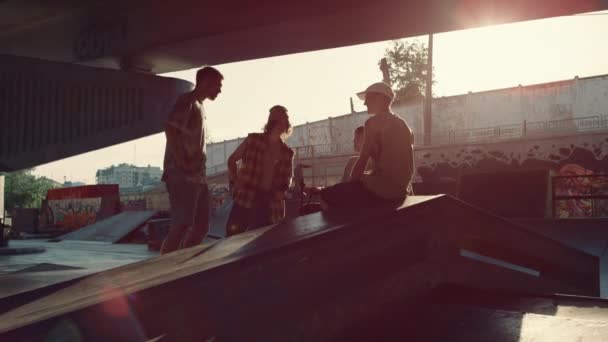 Elegantes millennials relaxante skatepark. Hipsters conversando juntos ao pôr do sol. — Vídeo de Stock