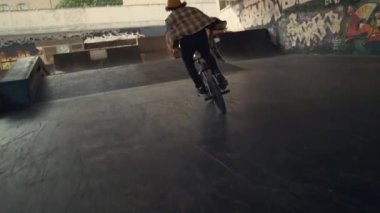 Genç motorcu, şehir kaykay parkında tren dublörlüğü yapıyor. Binici bmx üzerinde yarışıyor.