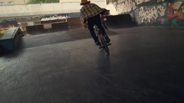 Giovane motociclista esibendosi acrobazia ferroviaria a skate park urbano. Pilota corse su bmx. — Video Stock
