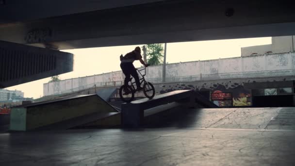 Extreme teenage man falling down while practicing jump stunt on bicycle at park. — Stock Video