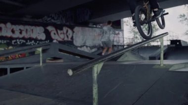 Aktif gençler paten yerinde eğleniyor. Bmx sürücüsü numara yapıyor. 