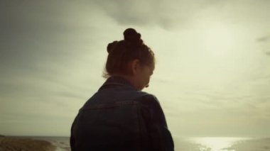 Küçük kız gün batımının tadını çıkarıyor. Tatlı çocuk tatilde taş deniz kabuğu oynar..