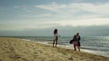 Neşeli bir aile deniz sahilinde güzel bir tatil yapıyor. Olumlu insanlar okyanusla oynar..