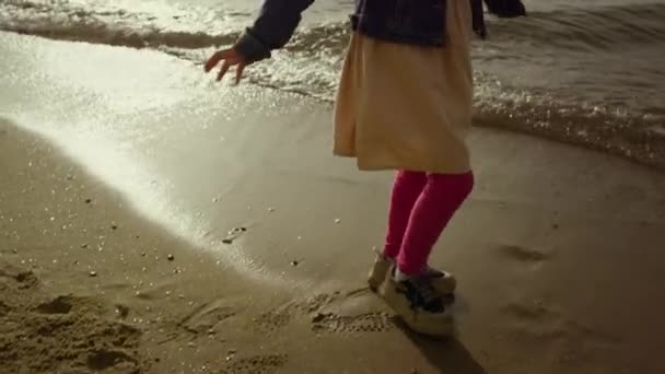 Fiatal lány táncol strand. Imádnivaló gyerek játszik egyedül napsütéses nap tenger partján homok — Stock videók