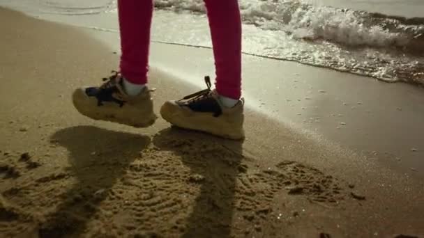 Child legs walking beach water at sea shore. Little girl dance at crashing waves — Stock Video