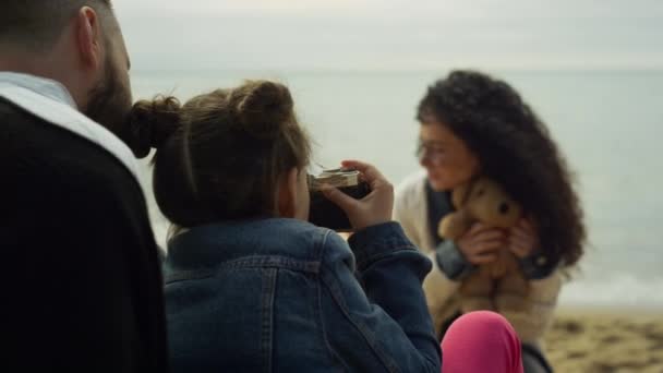 Family playing photo camera on sea beach. Parents child photographing teddy bear — Stock Video