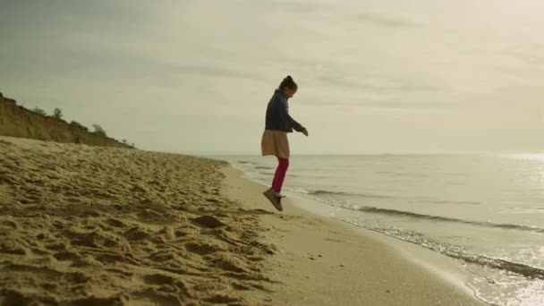 Klein meisje dat buiten speelt op zonsondergang strand. gelukkig kind ontspannen alleen aan zee — Stockvideo