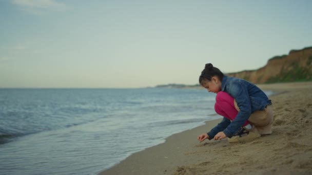 Cute girl gra piasek na plaży morskiej. Dzieciak cieszący się wakacjami na wybrzeżu przyrody. — Wideo stockowe