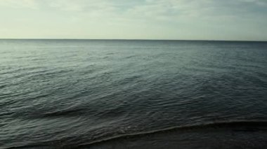 Sakin okyanus suyunun arka planında, dışarıda sakin bir doğa var. Gün batımında deniz dalgaları.