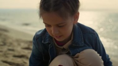 Deniz sahilinde kum çizen küçük kız. Okyanus kıyısında oyun oynayan sevimli çocuk..