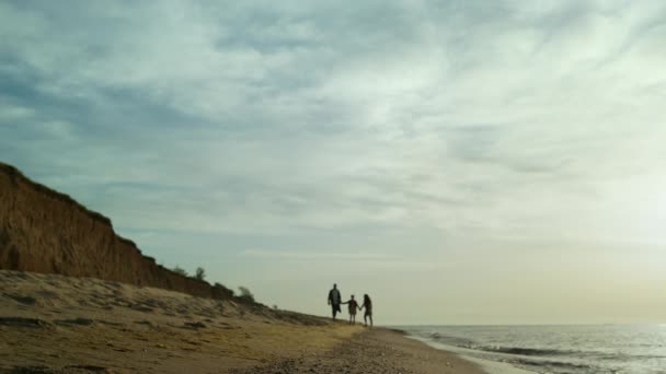 Deniz manzaralı sahilde yürüyen aile siluetleri. Tatil gevşeme kavramı. — Stok video