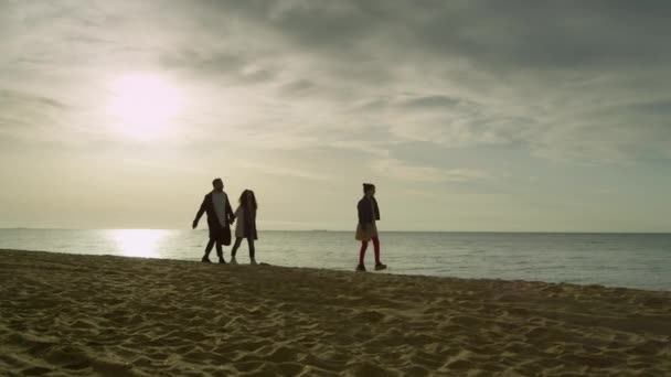 Alegre familia va playa puesta del sol cielo océano. Grupo de personas caminar en la costa del mar. — Vídeos de Stock
