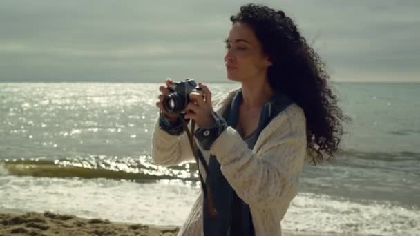 Mujer hispana tomando fotos en la orilla del mar. Bella dama fotografiando la naturaleza. — Vídeos de Stock