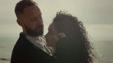 Genç çift romantik bir randevuda kumsalda flört eder. Güzel insanlar deniz kenarındaki kıvırcık saçlara dokunur.