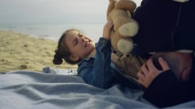 Küçük çocuk deniz sahilinde ebeveyncilik oynuyor. Aile deniz kıyısında birlikte vakit geçiriyor..