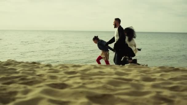 Speelse familie lopende strand zand. Jongeren die het naar hun zin hebben aan zee. — Stockvideo