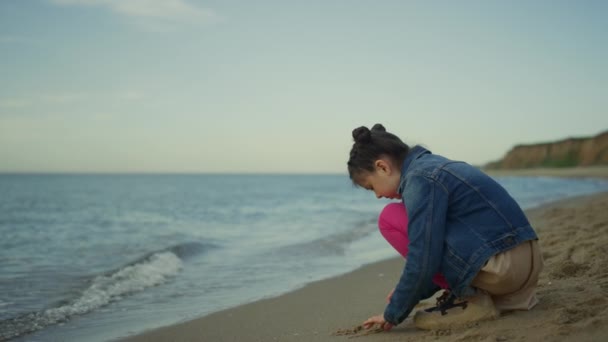 A gyerek homokot játszik a tengerparti családi kiránduláson. Kislány, tölts egy kis időt egyedül odakint. — Stock videók